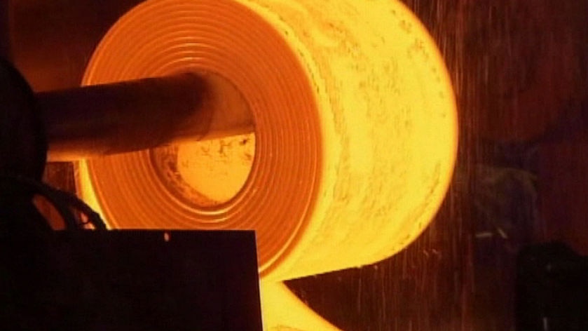 Red hot steel being rolled out at a mill.