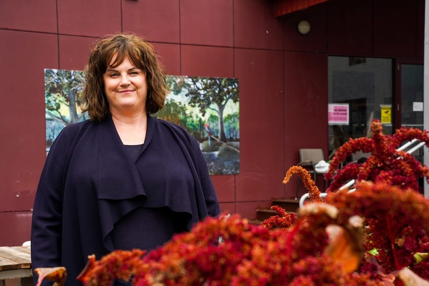 Bronwen Clark smiles with flowers in the foreground.