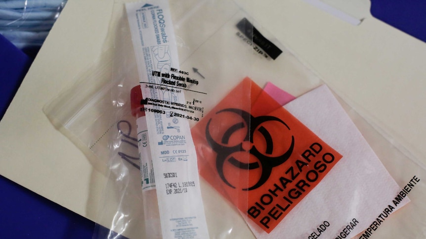 An unused test tube and swab kit marked biohazard are wrapped in plastic.