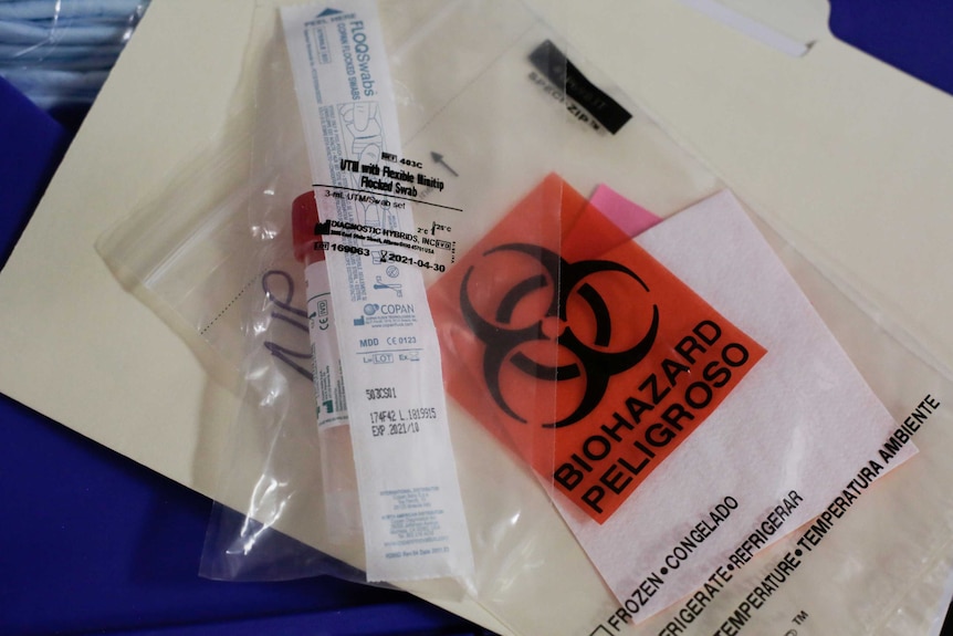 An unused test tube and swab kit marked biohazard are wrapped in plastic.