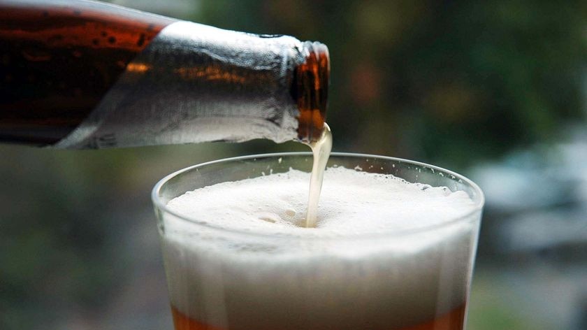 Beer from a bottle is poured into a glass.