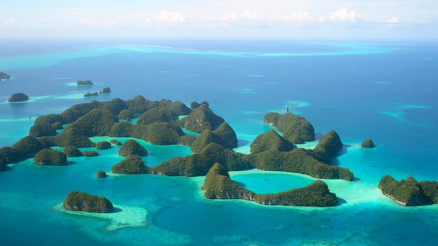 A chain of verdant islands sit in a bright blue and green sea, as seen in an aerial picture.