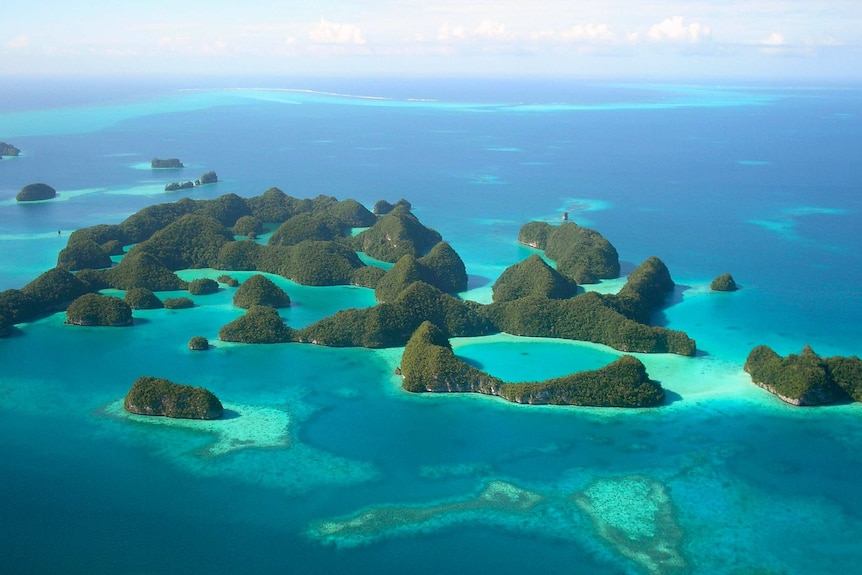 A chain of verdant islands sit in a bright blue and green sea, as seen in an aerial picture.