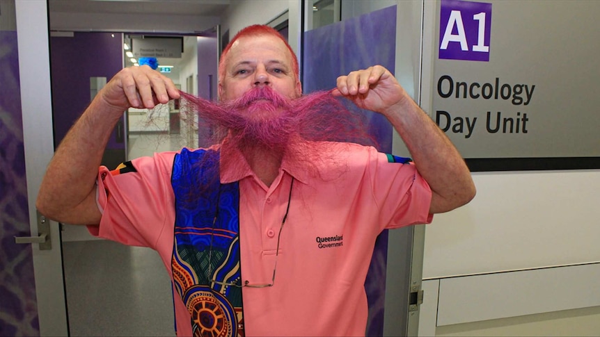 A man shows off his bright pink beard.