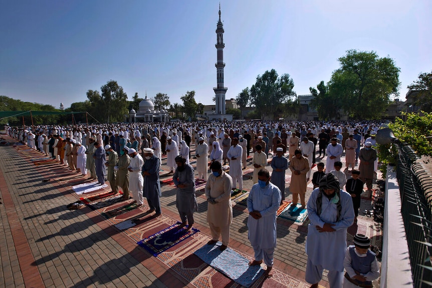 Muslim men praying outside a mosque in Pakistan, maintaining social distancing.