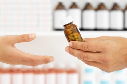 Pharmacist hands customer bottle of pills (Thinkstock: Stockbyte)