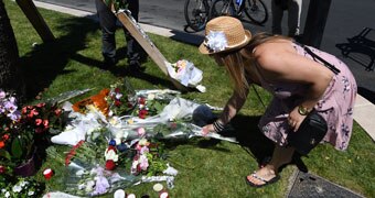 A woman lays flowers in Nice, where a truck drove in to a crowd of Bastille Day revellers, killing at least 84 people.