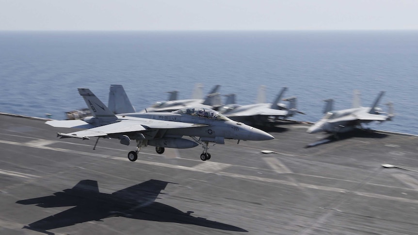 A US fighter jet lands on the flight deck of the USS Theodore Roosevelt aircraft carrier