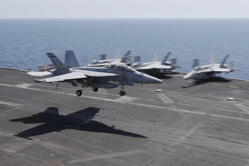 A US fighter jet lands on the flight deck of the USS Theodore Roosevelt aircraft carrier