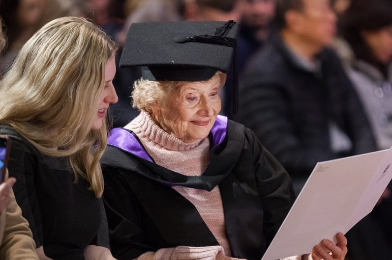 Lorna Prendergast sits next to her granddaughters in the audience as she examines a ceremony program.