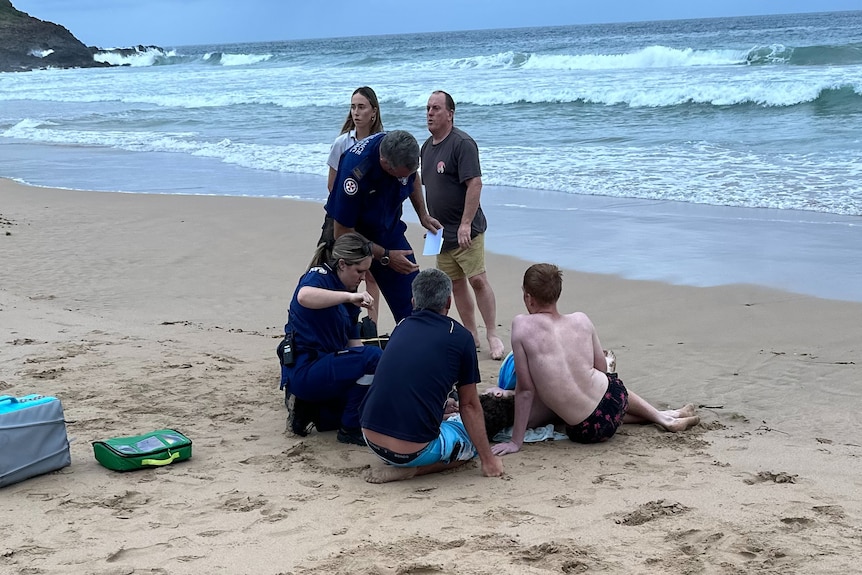 paramedics on sand with young boys at the beach