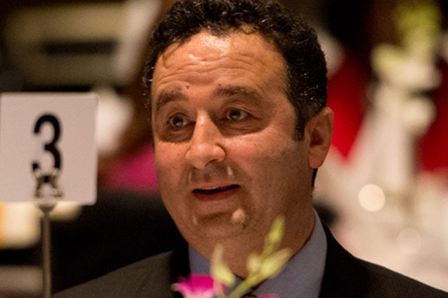 A man sits at a table wearing a suit and tie.