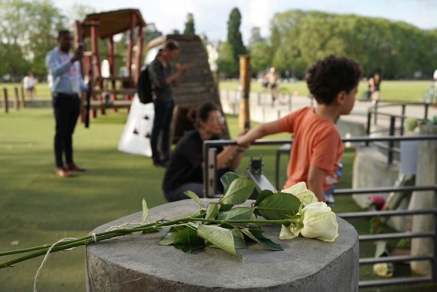 three white roses on a bolard in a park 