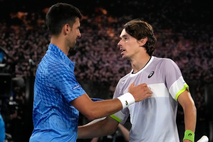 Die Tennisspieler Novak Djokovic und Alex de Minaur gratulieren sich bei den Australian Open über das Netz.