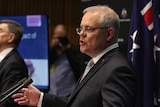 Scott Morrison in a suit and grey tie mid sentence standing next to the chief medical officer at a press conference.