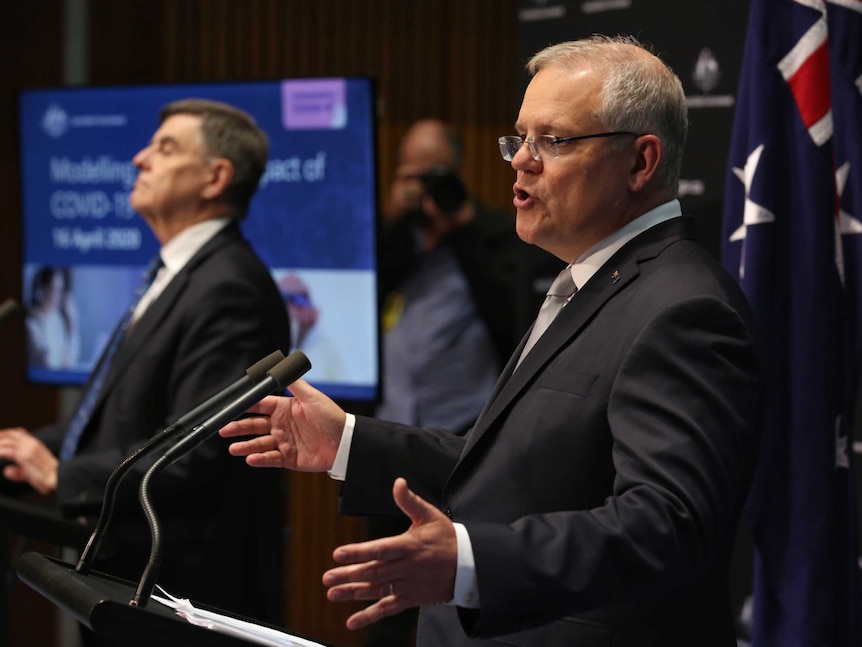 Scott Morrison in a suit and grey tie mid sentence standing next to the chief medical officer at a press conference.