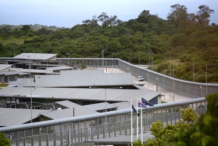 A complex with a high security fence and satellite dishes and flags.