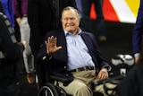Former president Geroge H.W Bush waves as he arrives at NRG stadium in his wheelchair.