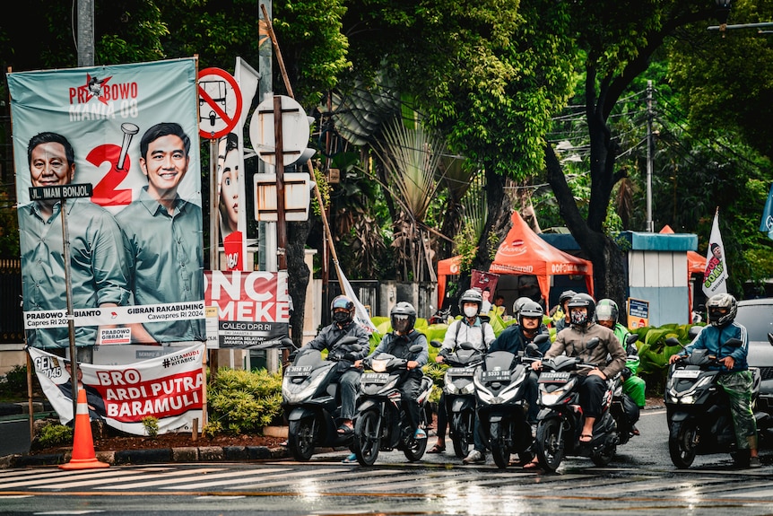 A street filled with Indonesian motorists displaying election signs for presidential candidates.