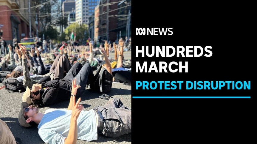 Hundreds March, Protest Disruption: Dozens of people lie on the ground razing their hands in the air.