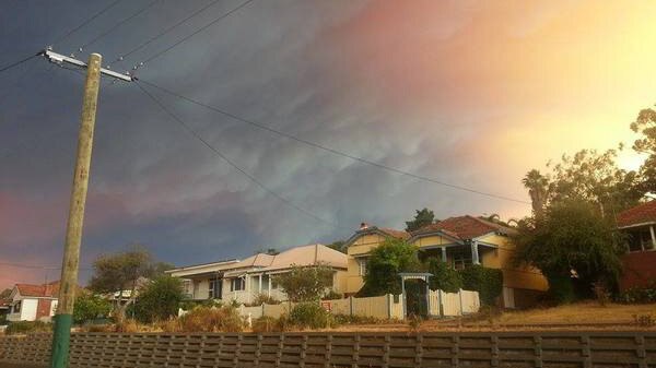 A sky half grey and half glowing from the Waroona bushfire looms over a Collie street.