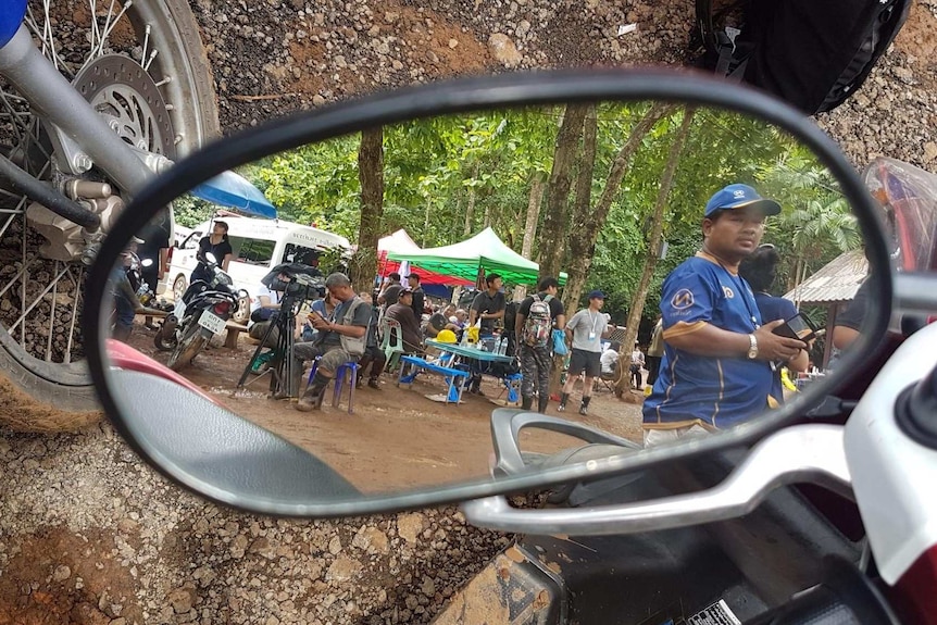 Volunteers and cameramen are reflected in a side mirror.