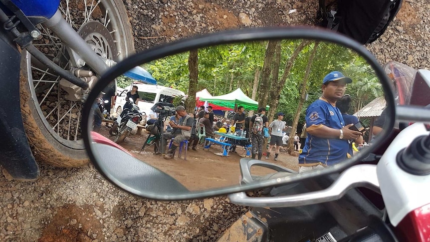 Volunteers and cameramen are reflected in a side mirror.