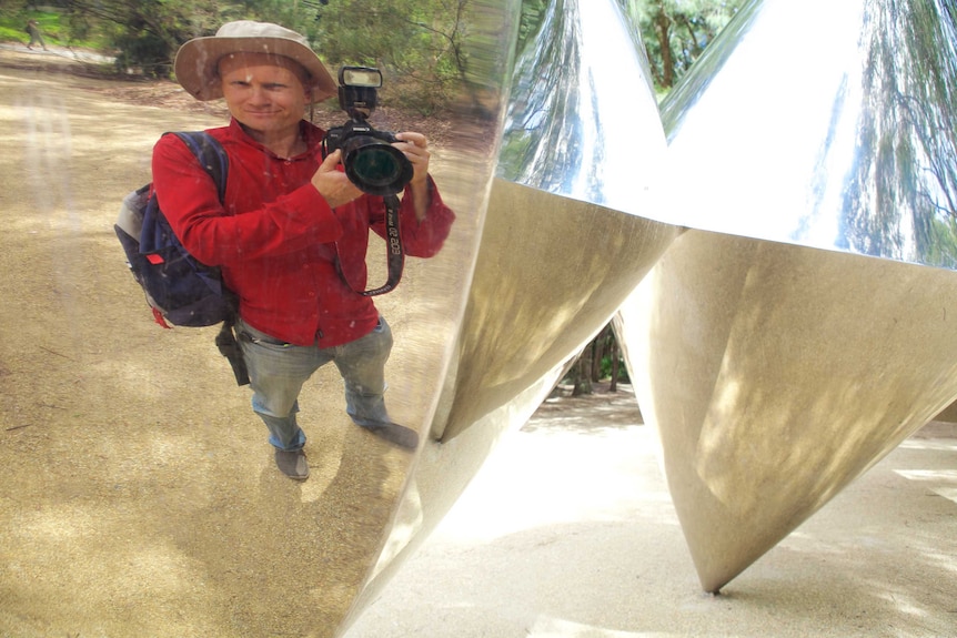 ABC Cameraman Nick Haggarty shoots his reflection in the Cones sculpture by Bert Flugelman.
