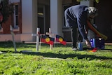 A woman places crosses in front of Geraldton Courthouse on the first day of the inquest into the death of JC.