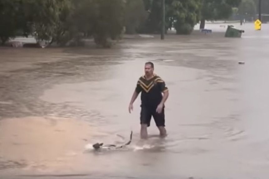 A man and a wallaby in floodwaters.