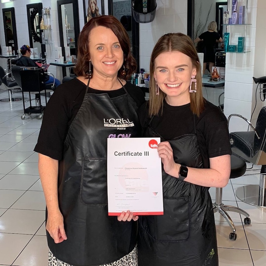 The woman is standing next to a young woman holding three certificates.