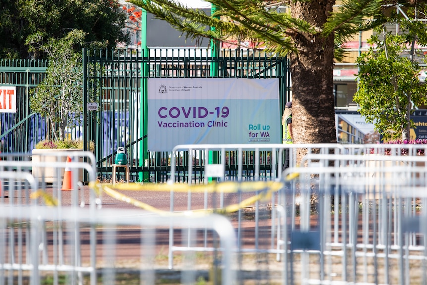 A sign hanging on a gate reading 'COVID-19 Vaccination Clinic'.
