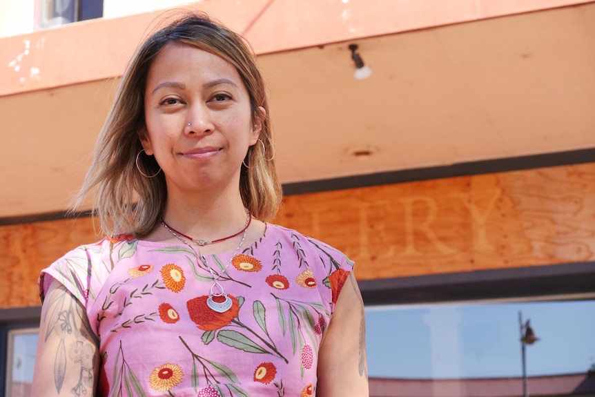 A close up of a woman with brown hair wearing a patterned shirt.