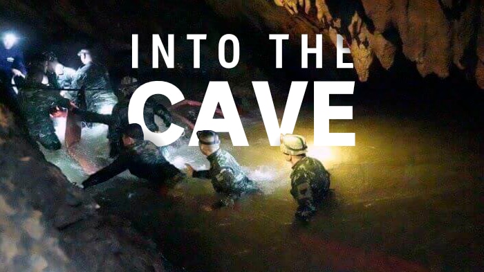 A group of rescuers travel into the cave. The words 'Into the cave' are transposed into the image.