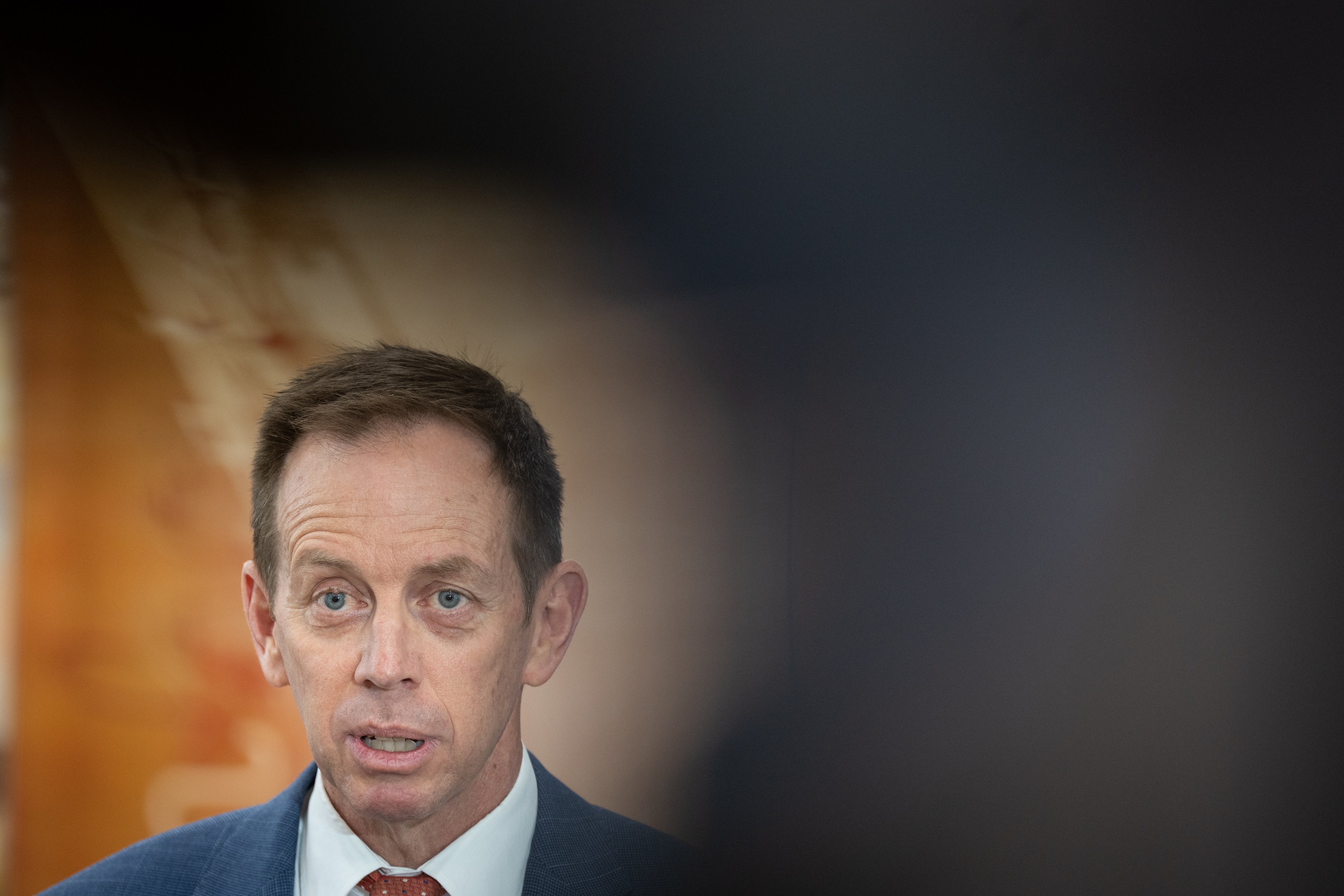 Shane Rattenbury in the spotlight between a media pack.