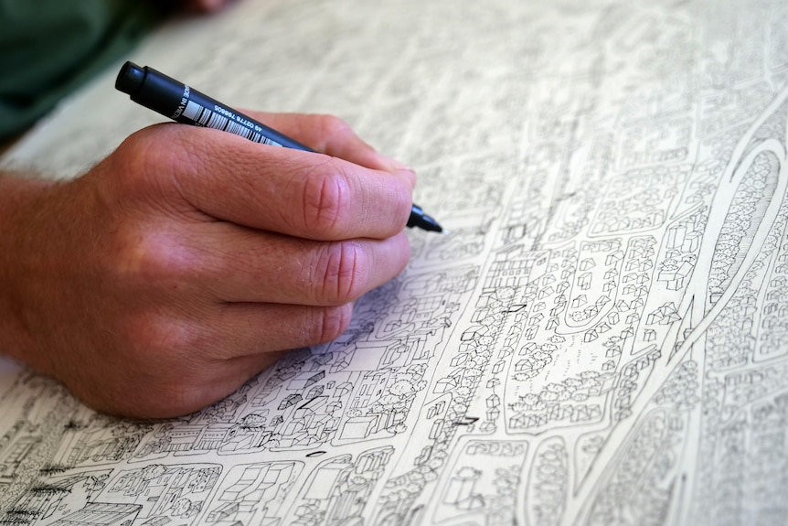 A close-up photo of Alex's hand holding a pen and drawing details on his Wollongong map.
