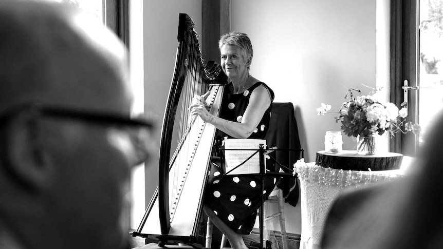 A black and white photograph of a woman playing the harp.