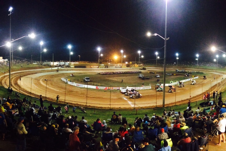 It's dark, but down below is a dirt speedway with cars zooming along it