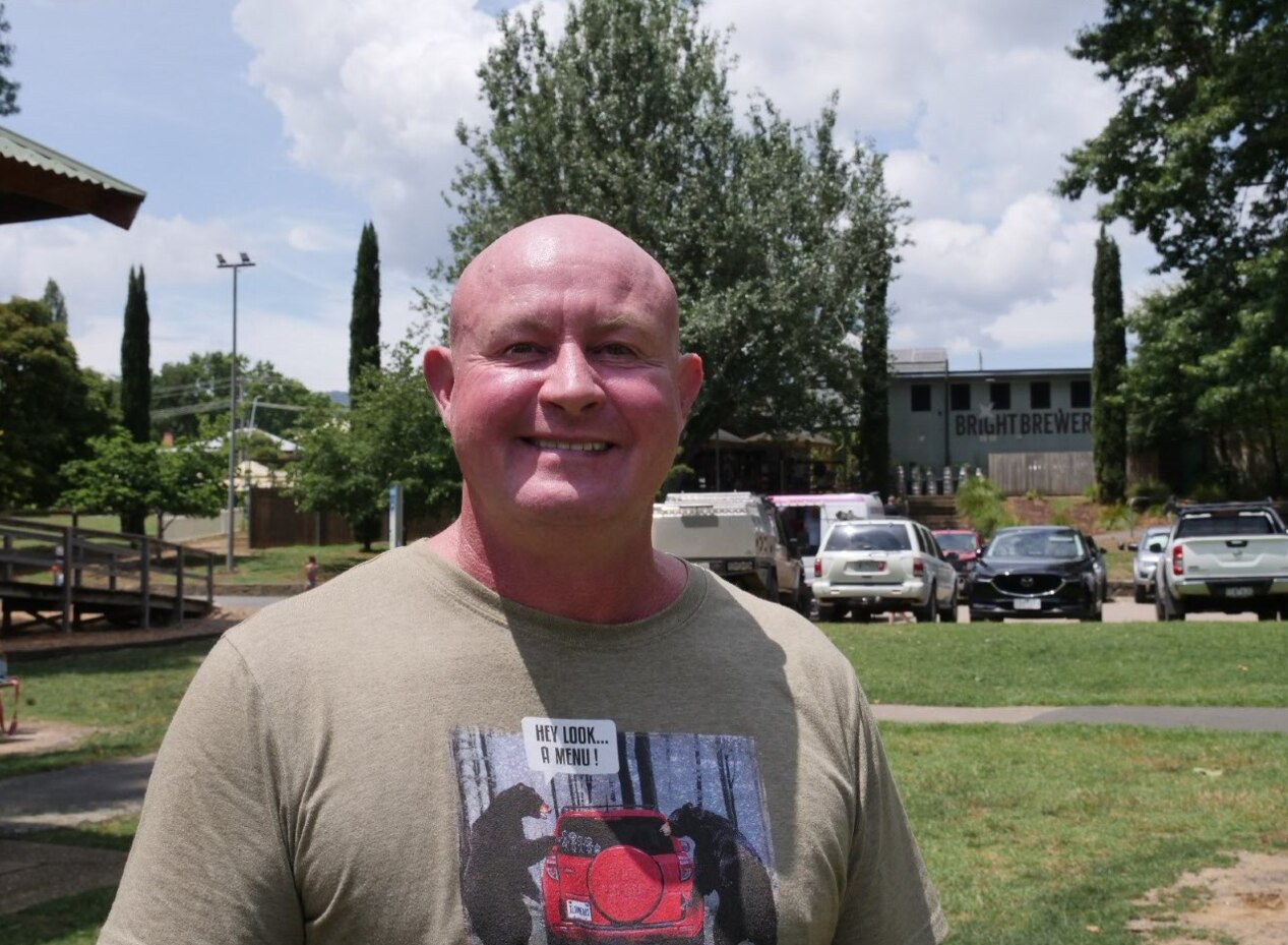 Bald middle-aged man, wearing tee shirt smiles at camera 