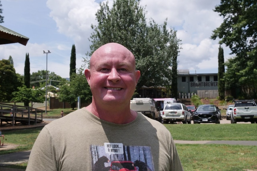 Bald middle-aged man, wearing tee shirt smiles at camera 