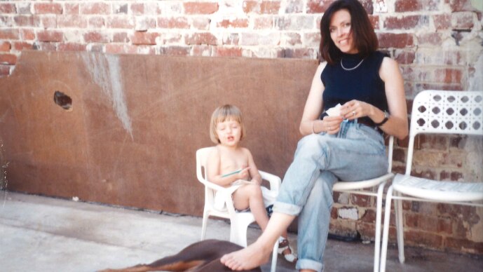 Judi Green sitting with her daughter, Portia Green, against an exposed brick wall.
