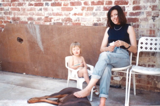 Judi Green sitting with her daughter, Portia Green, against an exposed brick wall.