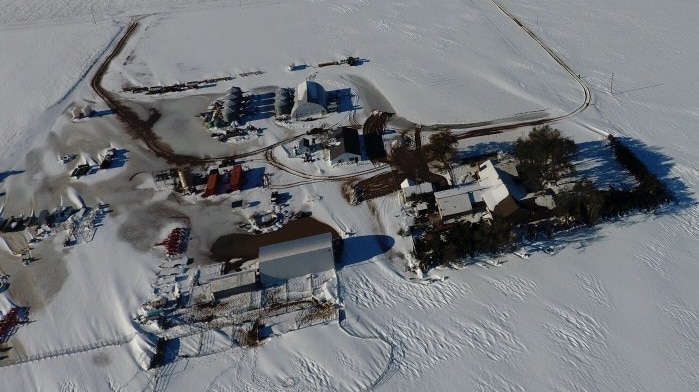 an aerial shot of a farm covered in white snowfall
