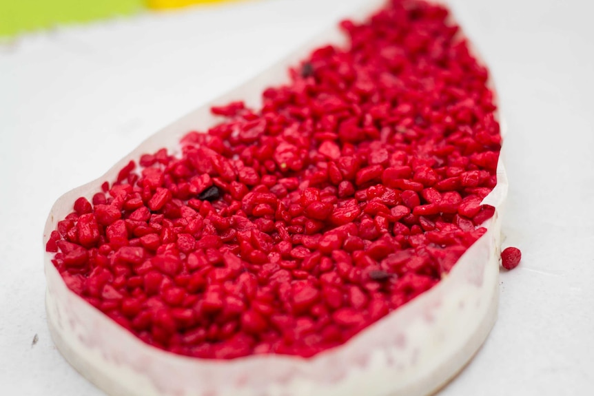 A container of red-coloured gravel sits on a table.