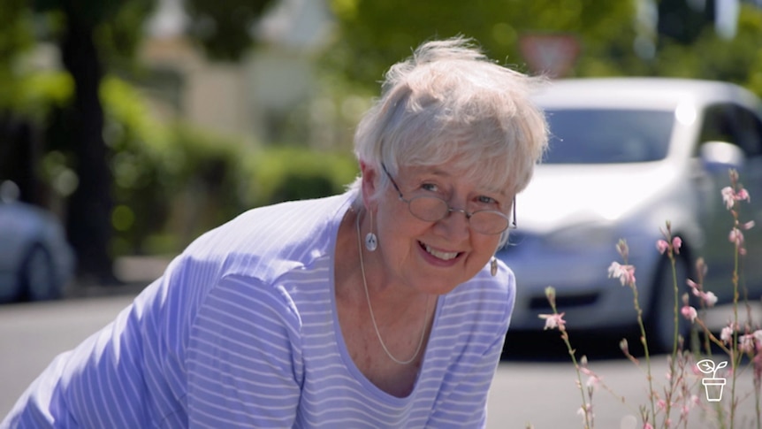 Lady smiling leaning over garden bed