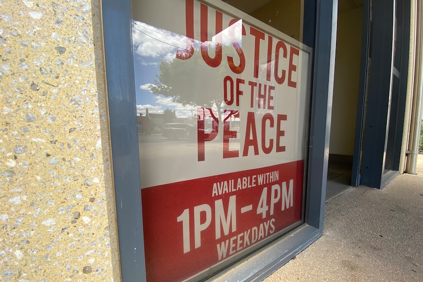 A red a white sign reads Justice of the Peace: Available within 1pm to 4pm weekdays.