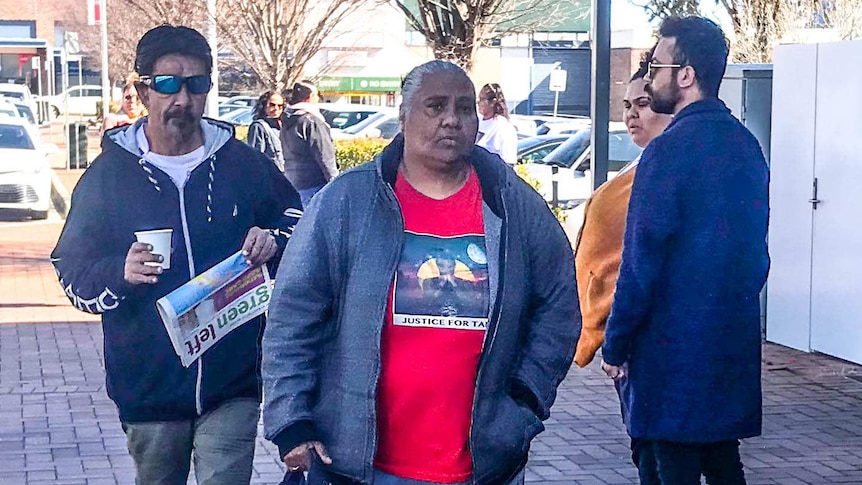 A man and a woman look solemnly at the camera while walking into court