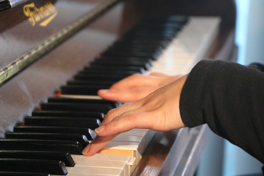 A woman's hands while playing a piano.