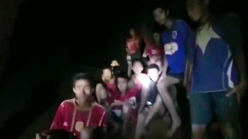 Screenshot taken from video shows blurred faces of boys looking at rescuers.