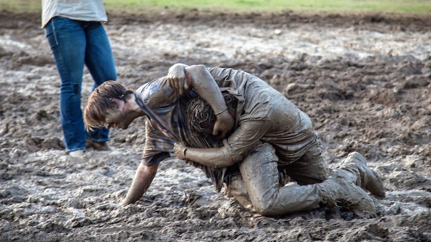 Two young men wrestle in the mud in at the 2022 Koonoomoo B and S Ball.